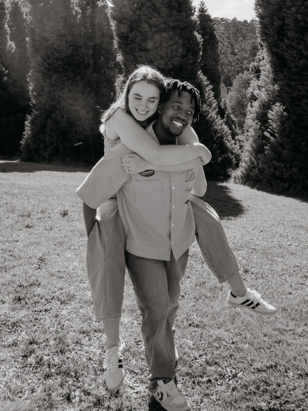 Black-and-white photograph of Amelia laughing on Quinton’s back