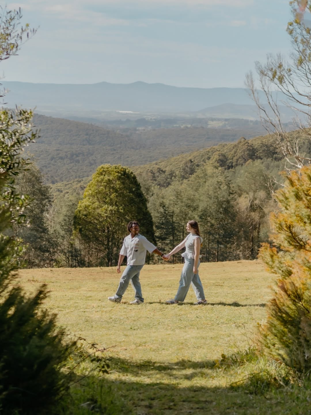 Amelia and Quinton holding hands on a garden hillside with mountain views