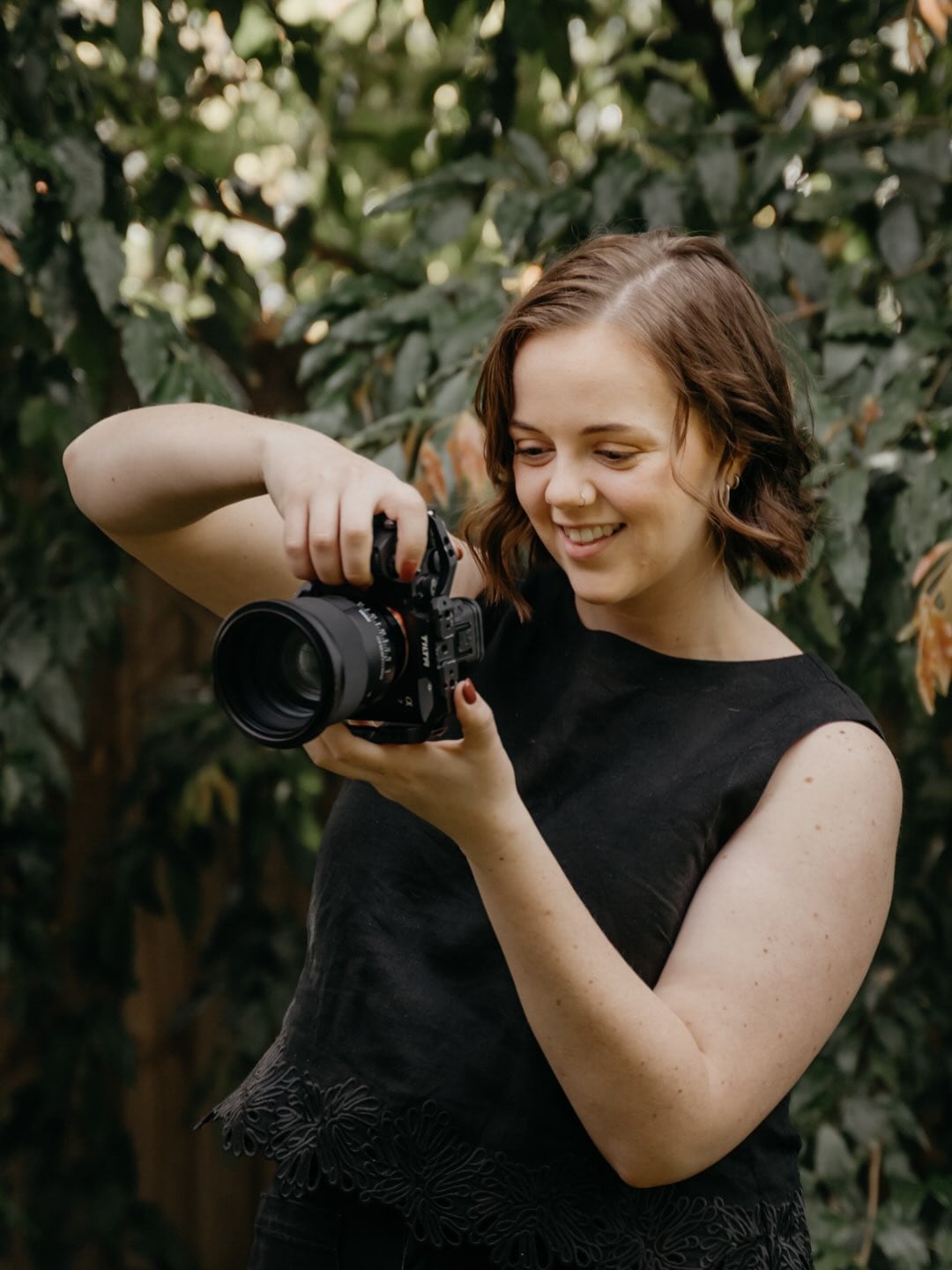 Keely smiling as she looks at her camera