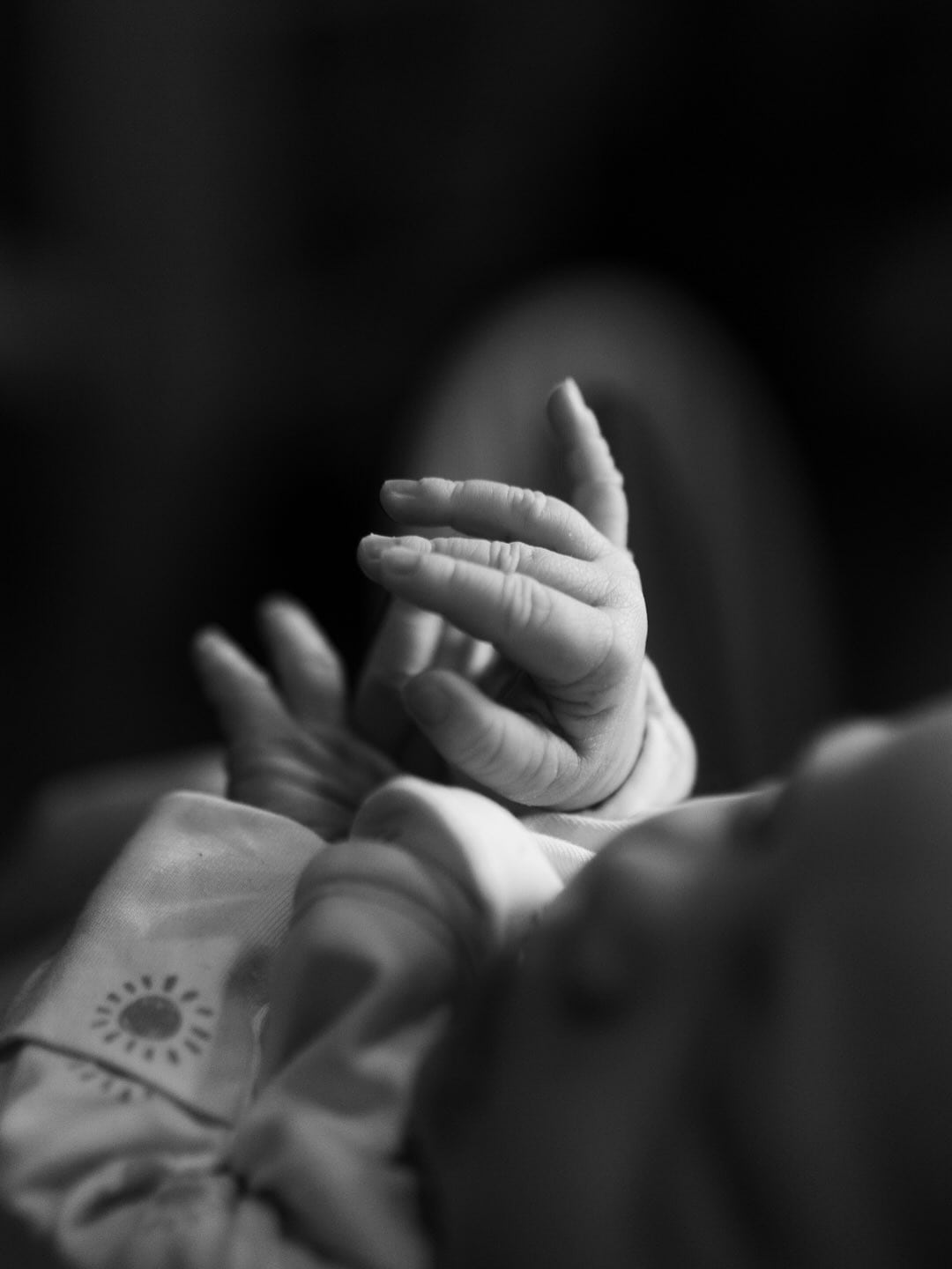 Black-and-white close-up of a newborn’s tiny hands